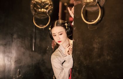 身穿古代汉服的美女在大门口偷偷张望