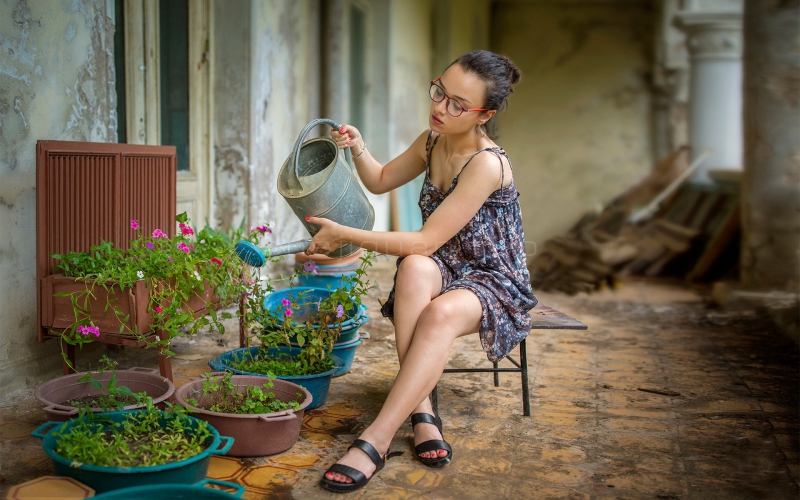 一位身穿吊带长裙的美女在自家远中浇花