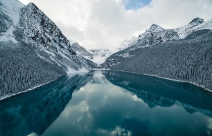 冬季群山上白雪河两岸的树林披着白雪河水蓝色倒映着天空的云彩